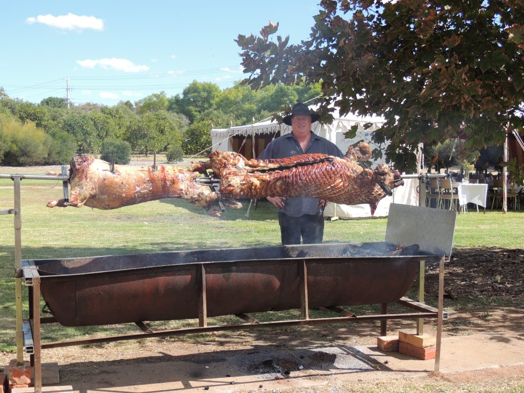 Large spit roaster cooking a whole pig and lamb